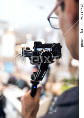 Adult professional videographer shooting using new steadycam. He looking at result on display screen 60347738