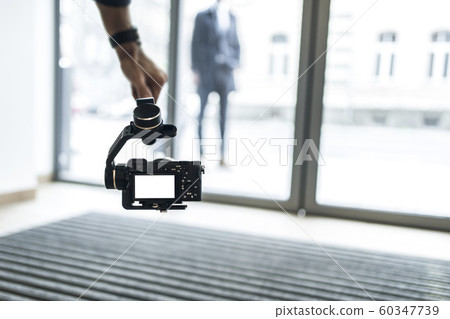 Adult professional videographer shooting using mirrorless camera on steadycam.  60347739