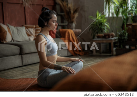 Beautiful young woman practicing yoga at home 60348518