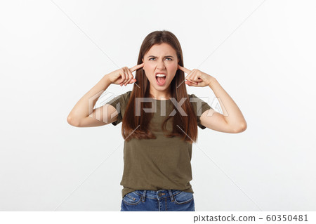 Closeup portrait of a young angry woman covering her ears, stop making that loud noise it's giving me a headache, isolated on white background. Closeup portrait of a young angry woman covering her ears, stop making that loud noise it's giving me a headache, isolated on white background. 60350481