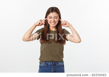 Closeup portrait of a young angry woman covering her ears, stop making that loud noise it's giving me a headache, isolated on white background. Closeup portrait of a young angry woman covering her ears, stop making that loud noise it's giving me a headache, isolated on white background. 60350483