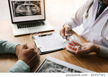 Asian man dentist is holding dentures jaw showing 60357341