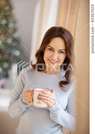 Pretty yuoung woman with cup in her hands smiling nicely Pretty yuoung woman with cup in her hands smiling nicely 60367029