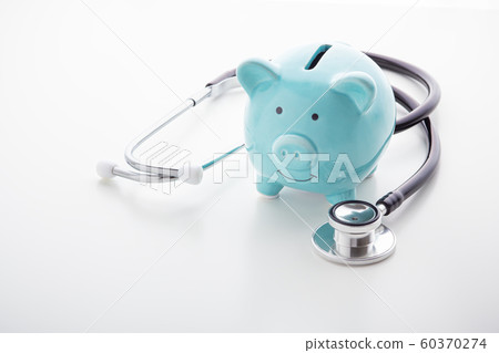 Piggy bank with stethoscope on white table Piggy bank with stethoscope on white table 60370274