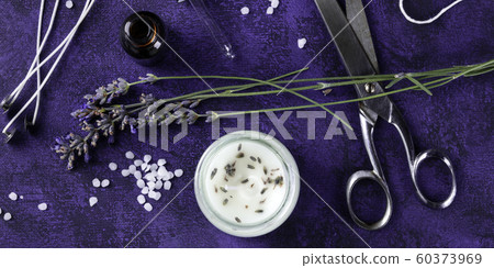 A panorama of a handmade lavender scented candle with essential oil, flowers, wax, wicks, a flat lay top shot on a dark purple background. An artisanal New Year gift, zero waste Christmas concept A panorama of a handmade lavender scented candle with essential oil, flowers, wax, wicks, a flat lay top shot on a dark purple background. An artisanal New Year gift, zero waste Christmas concept 60373969