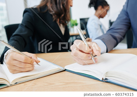 Business people writing in planners Business people writing in planners 60374315