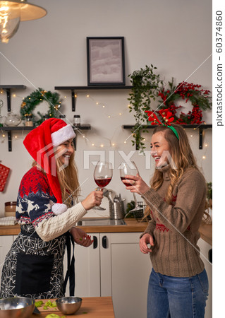 Two young women with wine glass standing in kitchen at christmas. New year concept 60374860