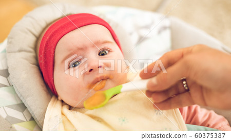 Mother feeding hungry five month old funny baby 60375387