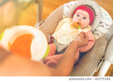 Mother feeding hungry five month old funny baby 60375389