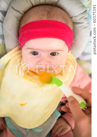 Mother feeding hungry five month old funny baby 60375391