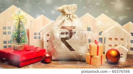 Money bag, wooden houses, Christmas tree and gifts. Christmas Sale of Real Estate. New Year discounts for buying housing. Purchase apartments at a low price. Holiday discounts. Rupee, rupiah Money bag, wooden houses, Christmas tree and gifts. Christmas Sale of Real Estate. New Year discounts for buying housing. Purchase apartments at a low price. Holiday discounts. Rupee, rupiah 60376566