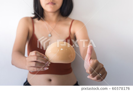 Woman hands holding silicone implants for breast and showing thumb up,Copy space for text on white background Woman hands holding silicone implants for breast and showing thumb up,Copy space for text on white background 60378176