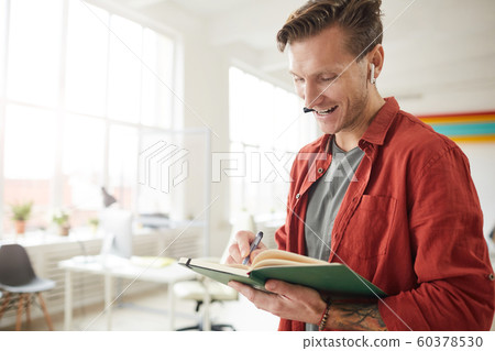 Smiling Adult Man Writing in Planner Smiling Adult Man Writing in Planner 60378530