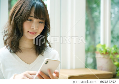 Image of woman operating smartphone at home 60381252
