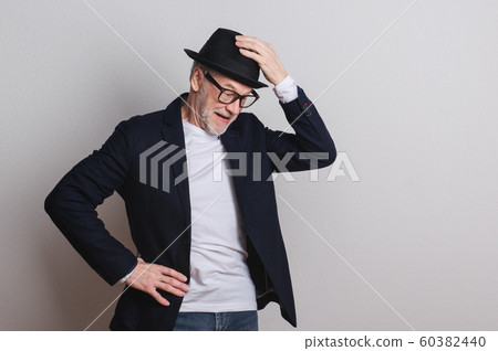 Portrait of a senior man with hat and glasses in a studio. 60382440