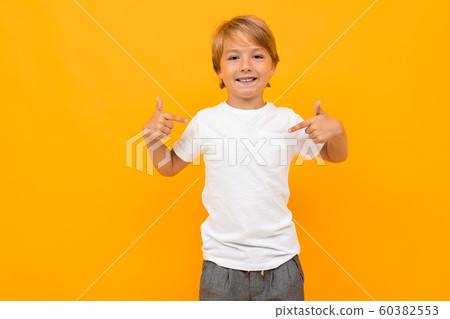 attractive european boy in a white t-shirt with mockup on an orange background with copy space 60382553