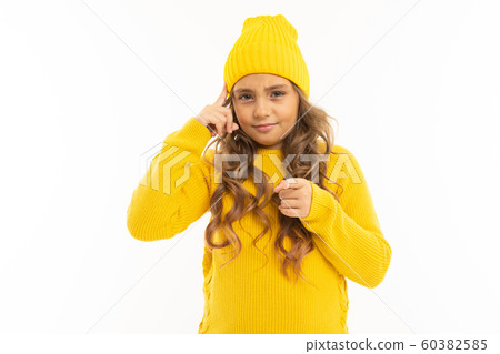European attractive girl in a yellow hat twists at the temple on a white background 60382585