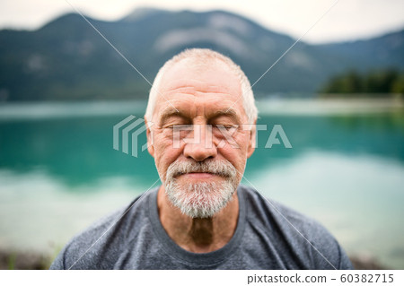A front view portrait of senior man pensioner standing outdoors in nature. A front view portrait of senior man pensioner standing outdoors in nature. 60382715