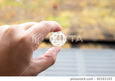 Man hold japanese coin 500 yen on blurred background 60383185