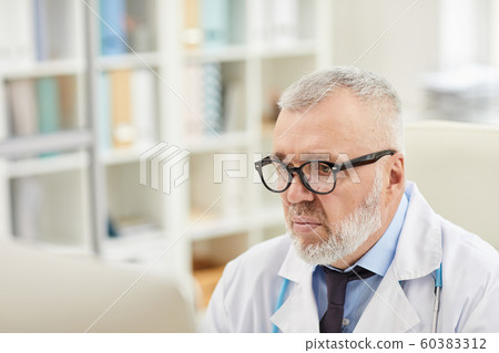 Mature doctor working at office Mature doctor working at office 60383312