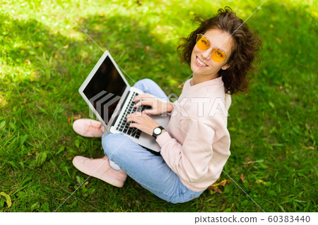 Pretty young caucasian woman is engaged in freelance in the park with laptop Pretty young caucasian woman is engaged in freelance in the park with laptop 60383440
