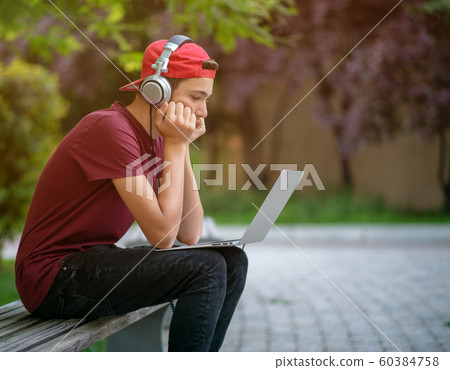 Teenage boy with a laptop in the park. Handsome Teenage boy with a laptop in the park. Handsome 60384758