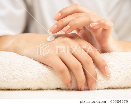 Woman applies a cosmetic moisturizer on her hands. 60384979