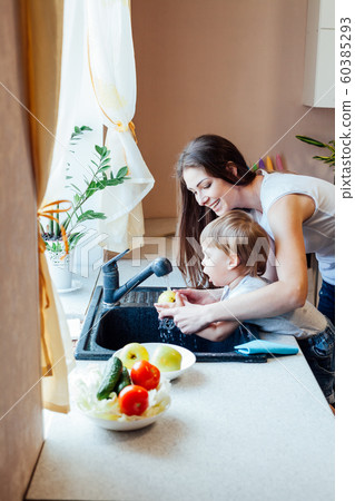 the little boy is helping mom in the kitchen 60385293