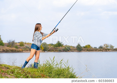 Beautiful young girl fishes on the lake. 60386663