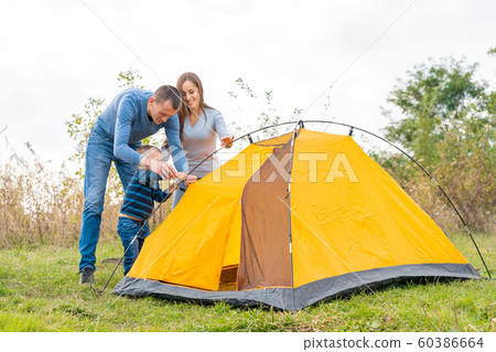Happy family with little son set up camping tent. Happy family with little son set up camping tent. 60386664