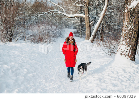 Young woman with her cute dog Husky on a walk in winter forest 60387329