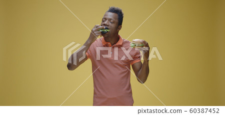 Young man eating two sandwiches 60387452