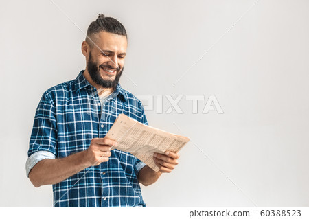 Freestyle. Guy in checkered shirt standing isolated on white reading newspaper smiling cheerful copy space Freestyle. Guy in checkered shirt standing isolated on white reading newspaper smiling cheerful copy space 60388523