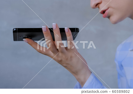 Woman holding smartphone and using voice recognition function - close up view Woman holding smartphone and using voice recognition function - close up view 60389802