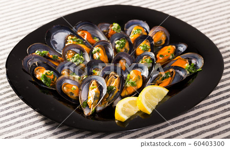 Baked mussels with lemon on black plate Baked mussels with lemon on black plate 60403300