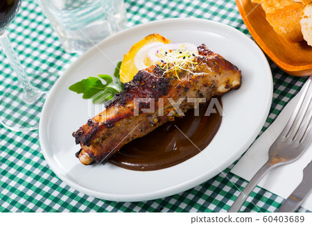 Tasty pork ribs baked under a mustard sauce, served with spicy sauce Tasty pork ribs baked under a mustard sauce, served with spicy sauce 60403689