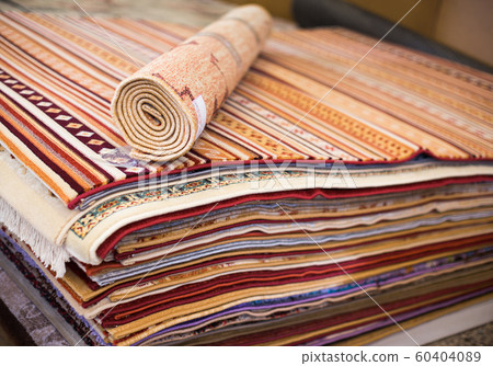 Stack of multicolored quality rugs at carpet shop 60404089