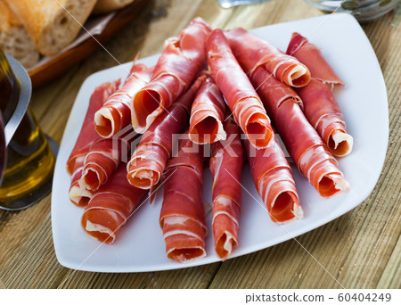 Dry-cured ham slices on white platter Dry-cured ham slices on white platter 60404249