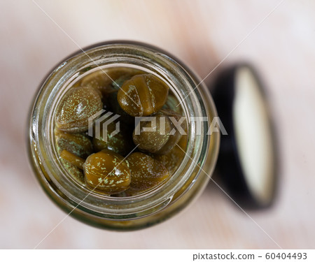 Pickled capers in a glass jar on wooden table Pickled capers in a glass jar on wooden table 60404493