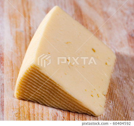 Slice of semi-soft cheese on a wooden table Slice of semi-soft cheese on a wooden table 60404592