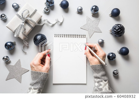 Woman writes goals, checklist, plans and dreams for New Year. Wish list for Christmas on classic blue Holiday decor. Woman writes goals, checklist, plans and dreams for New Year. Wish list for Christmas on classic blue Holiday decor. 60408932