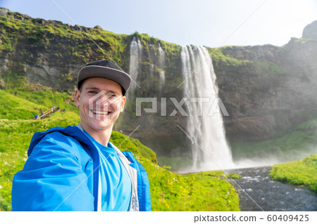 Young man taking selfie with beautiful waterfall of Seljalandsfoss on background. Concept of Young man taking selfie with beautiful waterfall of Seljalandsfoss on background. Concept of 60409425