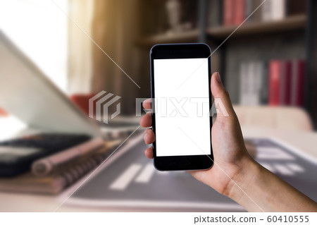 Hand holding white mobile phone with blank white screen  in office. 60410555