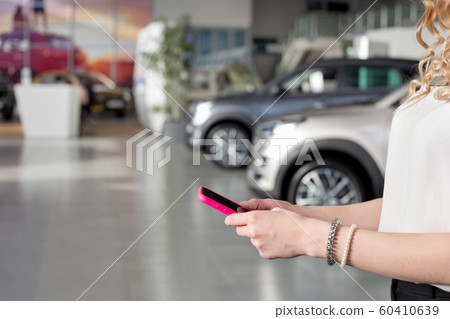 Woman dealer using mobile smart phone in showroom. Woman dealer using mobile smart phone in showroom. 60410639