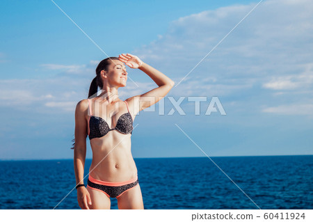 girl in bathing suit sunning on the beach by the sea 60411924