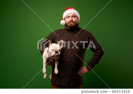 Man in santa hat with bulldog on empty green background Man in santa hat with bulldog on empty green background 60411928