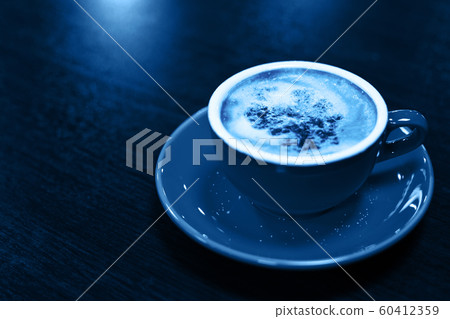 Color of year, 2020. Cup of cappuccino or latte on wooden background, toned classic blue photo. Coffee cup, top view. 60412359