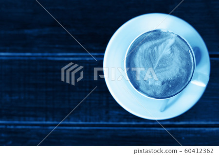 Color of year, 2020. Cup of cappuccino or latte on wooden background, toned classic blue photo. Coffee cup, top view. 60412362