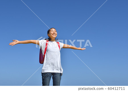 Elementary school girl spreading her hand in the blue sky (school bag) Elementary school girl spreading her hand in the blue sky (school bag) 60412711