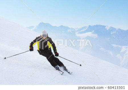 Alpine skier on piste running downhill 60413301
